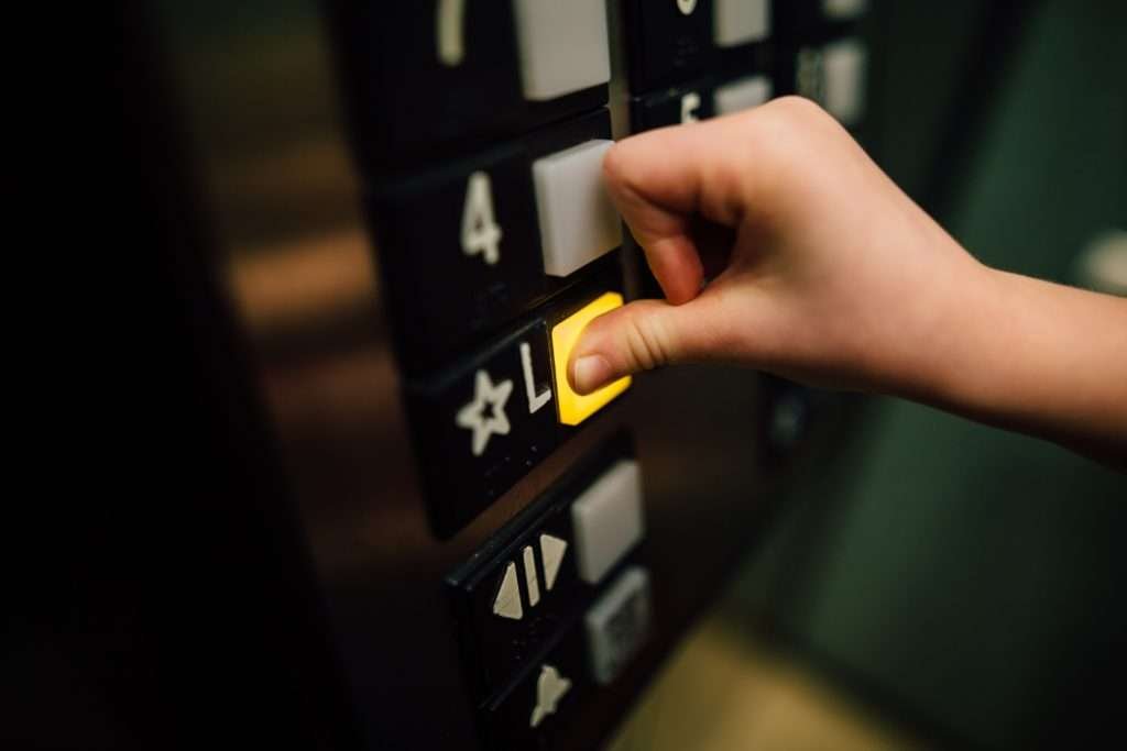 Main appuyant sur le bouton d’un ascenseur