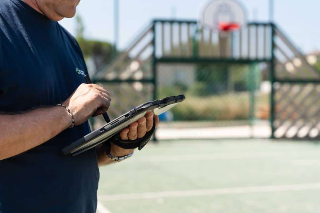 Un technicien Acritec note ses observations devant un terrain de basket